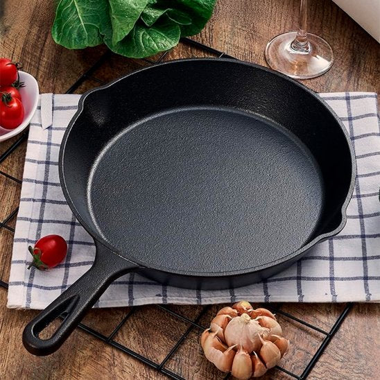 poele en fonte serviette tomate ail feuille verre table bois